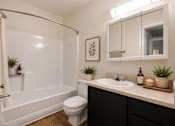 Thumbnail 8 of 17 - A bathroom with a white tub, toilet, and sink.