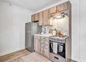 Thumbnail 2 of 37 - a kitchen with wooden cabinets and stainless steel appliances and a refrigerator at The Meriden, Meriden, CT