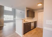 Thumbnail 1 of 22 - an empty kitchen with a white counter top and a door to a living room at Ardenwood Apartments, North Haven, CT, 06473