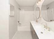 Thumbnail 13 of 22 - a white bathroom with a shower and a sink and a mirror at Ardenwood Apartments, North Haven, 06473