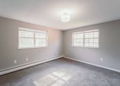 Thumbnail 13 of 24 - an empty bedroom with two windows and a carpeted floor at BAY SHORE APARTMENTS, EAST HAVEN, CT, 06512