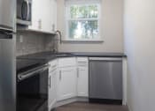 Thumbnail 12 of 19 - an empty kitchen with white cabinets and a black counter top  at Enclave West Hartford / Parc West, Connecticut