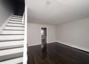 Thumbnail 36 of 39 - an empty living room with stairs and a white staircase at Encore 99, East Haven, CT, 06512