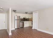 Thumbnail 15 of 24 - an empty living room with a kitchen with stainless steel appliances at Retro 511 Apartments, West Haven, CT 06516
