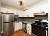 Thumbnail 6 of 24 - a modern kitchen with stainless steel appliances and white cabinets at Retro 511 Apartments, West Haven, Connecticut