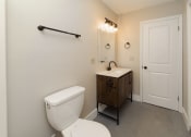 Thumbnail 21 of 24 - A white toilet sits next to a wooden cabinet in a bathroom at Retro 511 Apartments, Connecticut 06516