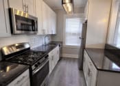 Thumbnail 53 of 55 - a kitchen with white cabinets and black counter tops at The Packard, West Hartford