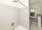 Thumbnail 32 of 55 - a white tiled bathroom with a tub and a toilet at The Packard, Connecticut