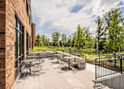 Thumbnail 15 of 23 - a patio with tables and chairs outside of a brick building
