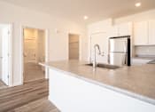 Thumbnail 10 of 33 - A kitchen with a white countertop and a stainless steel refrigerator.