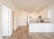 Thumbnail 11 of 33 - A kitchen with white cabinets and a wooden floor.