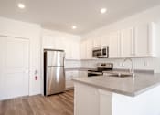 Thumbnail 12 of 33 - A kitchen with white cabinets and a stainless steel refrigerator.