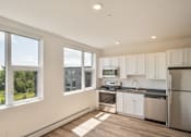 Thumbnail 6 of 23 - a kitchen with white cabinets and stainless steel appliances and large windows