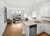 Thumbnail 14 of 32 - A modern kitchen with a dining area and a living room.
