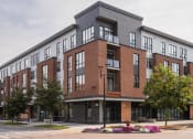 Thumbnail 24 of 41 - a red brick building with a gray roof on a city street
