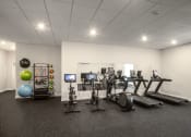 Thumbnail 37 of 41 - a gym with cardio equipment and weights in a room with white walls