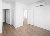 Thumbnail 20 of 30 - A room with white walls and wooden flooring, featuring a white door and a white cabinet.