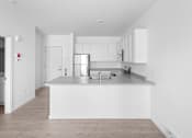 Thumbnail 28 of 30 - A kitchen with white cabinets and a wooden floor.
