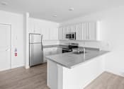 Thumbnail 29 of 30 - A kitchen with a stainless steel refrigerator, microwave, and sink.