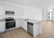 Thumbnail 27 of 30 - A kitchen with white cabinets and a wooden floor.
