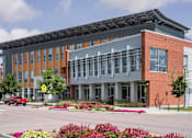 Thumbnail 33 of 42 - a large brick building with a metal roof and a parking lot in front of it