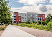 Thumbnail 28 of 42 - a large apartment building with a sidewalk in front of it