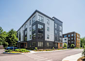 Thumbnail 25 of 30 - A modern multi-story building with a parking lot in front.