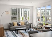 Thumbnail 13 of 30 - A modern living room with a grey sofa and a wooden side table.