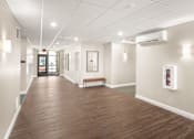 Thumbnail 4 of 30 - A long hallway with a bench and a fire extinguisher on the wall.