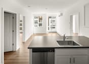 Thumbnail 26 of 30 - A modern kitchen with a black countertop and a stainless steel sink.
