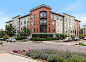 Thumbnail 42 of 44 - A street view of a multi-story building with a red brick facade and a green awning.
