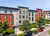Thumbnail 39 of 44 - A modern apartment complex with red and grey buildings.