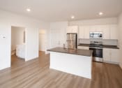 Thumbnail 13 of 41 - a large kitchen with white cabinets and a black counter top