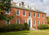 Thumbnail 4 of 24 - A red brick building with a white door and windows.