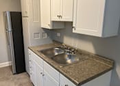 Thumbnail 23 of 24 - A kitchen with a sink and a refrigerator.