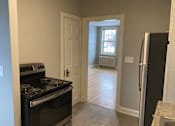 Thumbnail 17 of 24 - A kitchen with a black stove top oven and a black refrigerator.