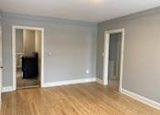 Thumbnail 12 of 24 - A room with light grey walls and wooden flooring with a white door and a mirror.