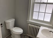 Thumbnail 11 of 24 - A white toilet sits next to a white sink in a bathroom.