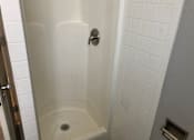 Thumbnail 19 of 24 - A white tiled shower stall with a drain in the middle.