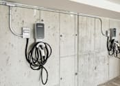 Thumbnail 11 of 18 - A wall with a charger and cables plugged into it.