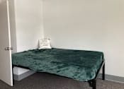 Thumbnail 7 of 15 - a small bed in a room with a green blanket