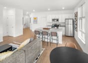 Thumbnail 12 of 30 - A modern kitchen with a grey couch and a black table.