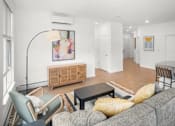 Thumbnail 4 of 30 - A living room with a grey couch, a wooden cabinet, and a painting on the wall.