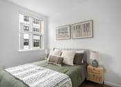 Thumbnail 11 of 30 - A bedroom with a bed, nightstand, and two framed artworks on the wall.