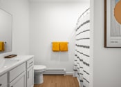 Thumbnail 8 of 30 - A bathroom with a toilet, sink, and a shower curtain.