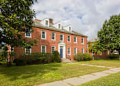 Thumbnail 6 of 24 - A red brick building with white trim and a white door.