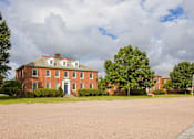 Thumbnail 9 of 24 - A red brick house with a white door and windows.
