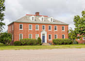 Thumbnail 8 of 24 - A red brick building with a white door and windows.