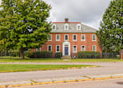Thumbnail 5 of 24 - A red brick house with a black fence in front.