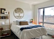 Thumbnail 10 of 17 - A bedroom with a large bed and a window overlooking a field.